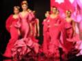 Modelos desfilando en la Feria de Abril de Sevilla, con vestidos de flamenca en colores vibrantes y detalles florales.