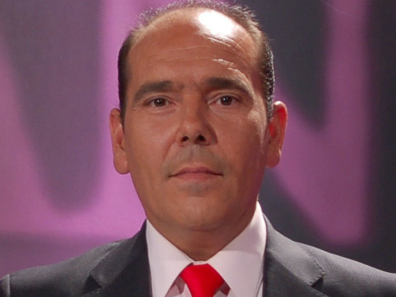 Un hombre con una camisa blanca y corbata roja, posiblemente en un evento formal.