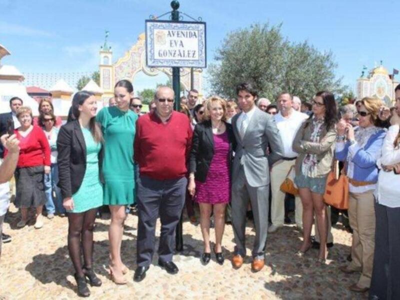 Una multitud de personas posa en una calle, algunos con sombreros y otros con gafas. La imagen muestra un ambiente festivo o ceremonial, posiblemente en una celebración o evento público.