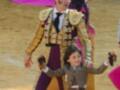 Un torero en traje tradicional junto a una niña en la plaza de toros.