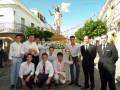 Un grupo de personas posa frente a una estatua de Cristo resucitado en un entorno festivo con banderas y decoraciones.