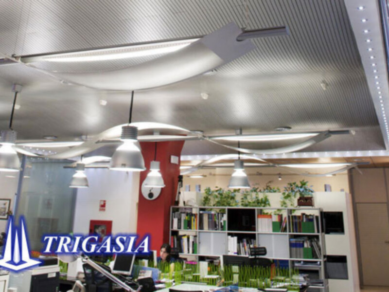 Interior de un espacio de trabajo moderno con techo de metal, iluminación LED y decoración con plantas verdes.
