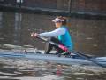 Atleta remando en un barco de regata en un canal urbano.