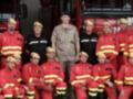Grupo de bomberos y soldados posando en uniformes militares.