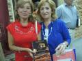 Dos personas posando con un libro en una feria del libro.