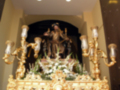 Altar con imagen de la Virgen y San Juan Bautista, adornado con flores y candelabros dorados.