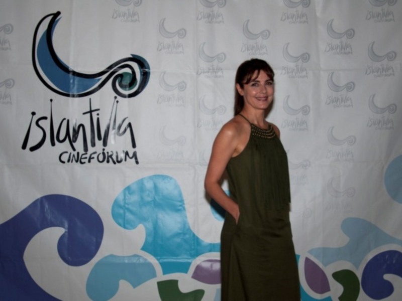 Invitada en el evento Islantilla Cinefórum, destacando con elegancia frente a un fondo con el logotipo del evento.