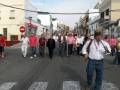 Procesión religiosa en una calle urbana, con participantes en trajes tradicionales y ornamentos festivos.