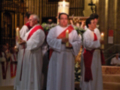 Imagen de un grupo de sacerdotes vestidos con hábitos blancos y rojos, posiblemente durante una ceremonia religiosa en un templo.