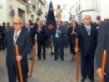 Una procesión religiosa en una calle de la ciudad, con personas vestidas formalmente y portando estatuas en una carroza.