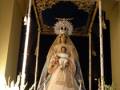 Procesión de la Virgen con el Niño Jesús en un trono ornado con flores y decoración dorada.
