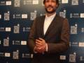 Un hombre con barba y cabello corto, posando frente a un fondo con el logo del Festival de Cine de Sevilla.