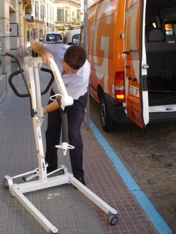 Persona ajustando un soporte de silla de ruedas en una calle urbana.