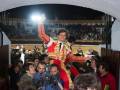 Un torero en traje tradicional celebra con el público en una plaza de toros.