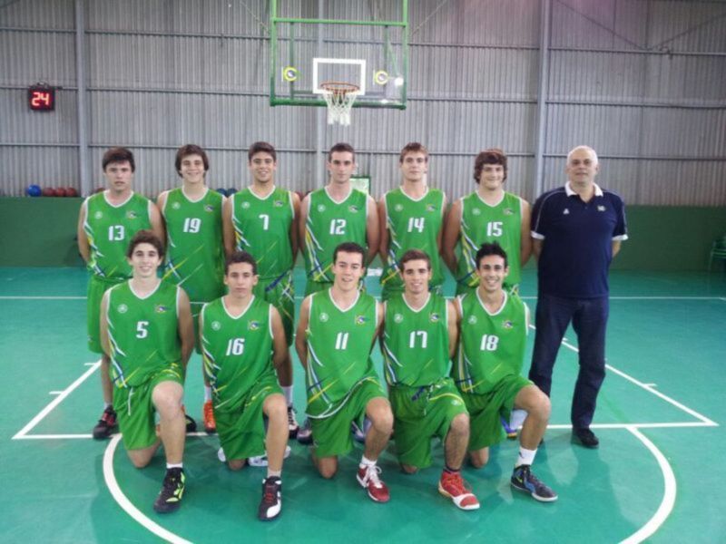 Equipo de baloncesto juvenil en uniforme verde con entrenador en cancha de baloncesto.
