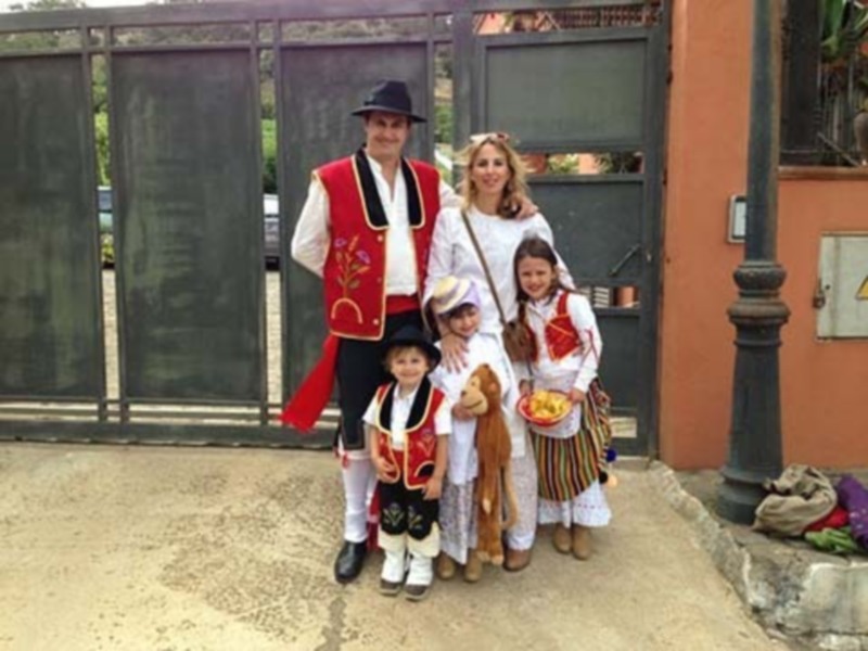 Familia vestida con trajes tradicionales posando frente a una puerta de madera.