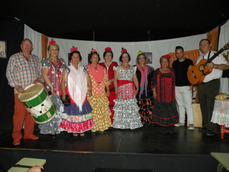 Grupo de personas vestidas con trajes típicos de flamenco en escenario.