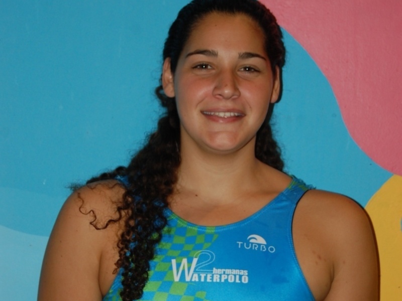 Retrato de una joven atleta de waterpolo, sonriendo frente a un fondo de colores vibrantes.