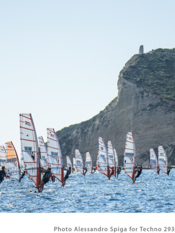 Competidores de vela de viento en el Techno 293 Worlds 2015 en Cagliari, Italia, con un impresionante acantilado en el fondo.