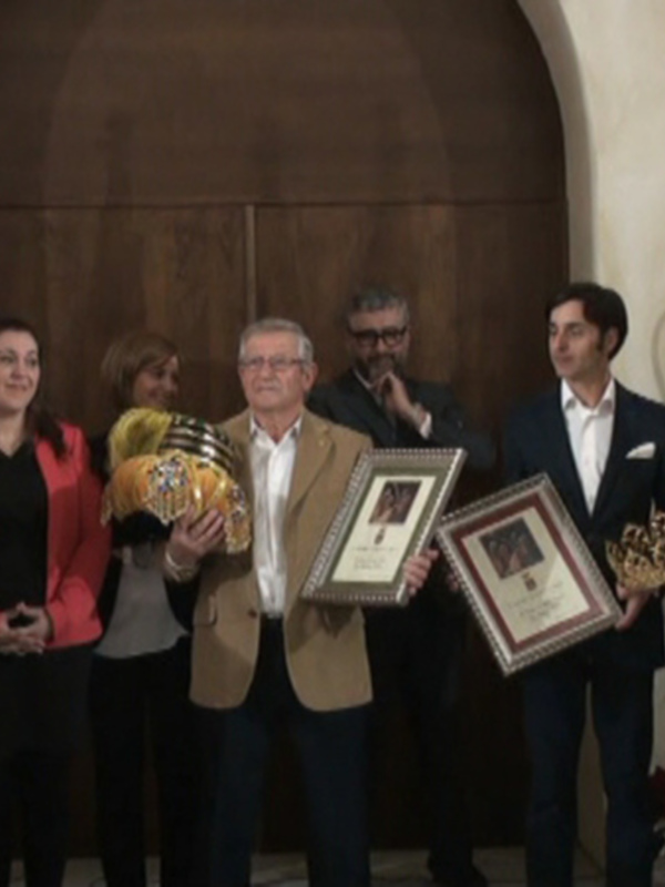Entrega de premios en una ceremonia oficial con banderas y escudos de la localidad.