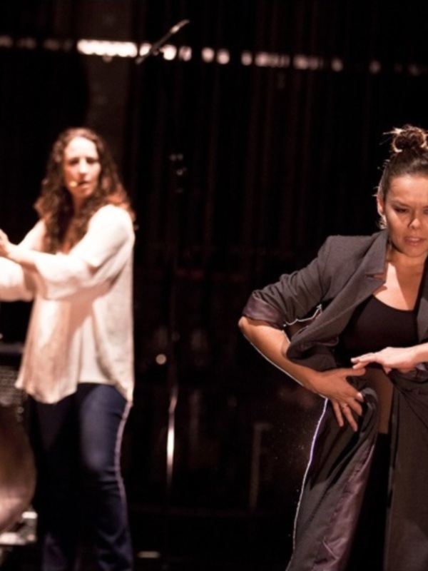 Tres artistas en escena, uno tocando el contrabajo, otro bailando y la tercera realizando una danza fluida.