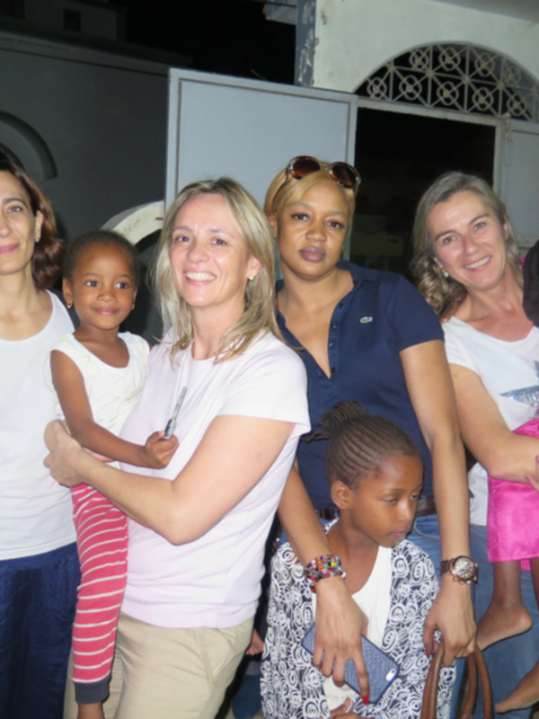 Un grupo de mujeres y niñas sonríen juntas en un ambiente nocturno, posando con una mezcla de alegría y amistad.
