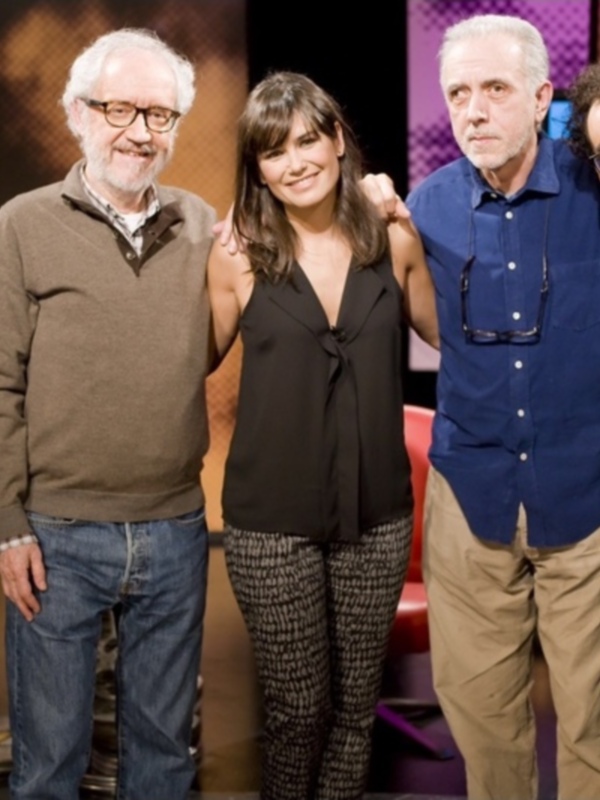 Un grupo de cinco personas posa juntos en un estudio de televisión, sonrientes y relajados.