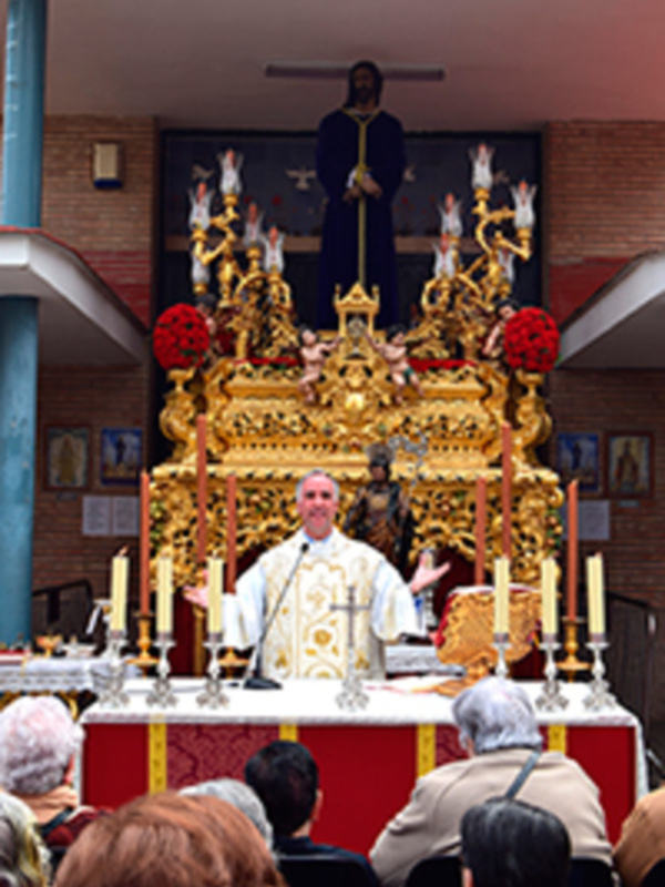Celebración religiosa con sacerdote oficiando en un altar adornado con velas y estatuas religiosas.