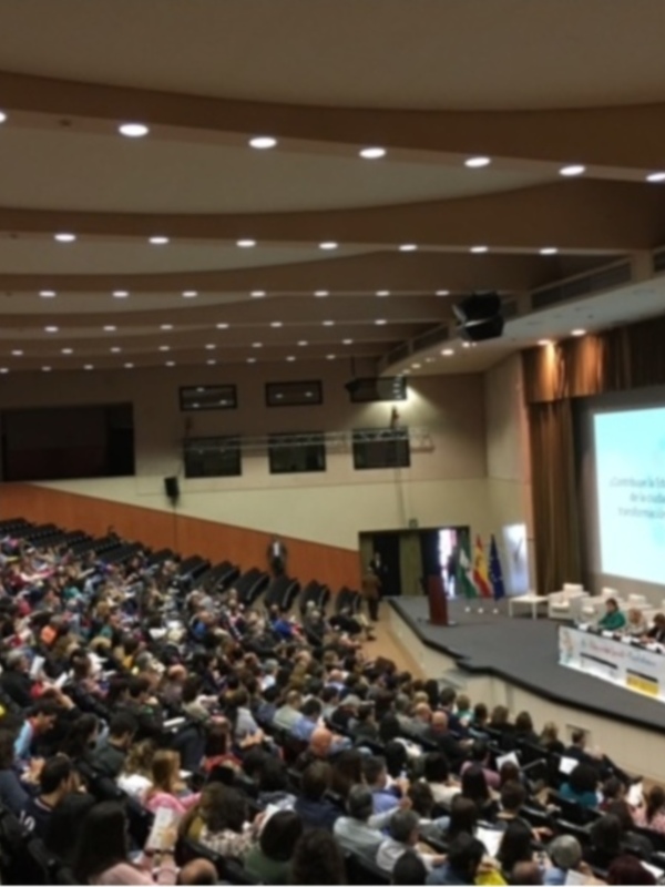Conferencia en auditorio lleno con pantalla proyectando texto en español.