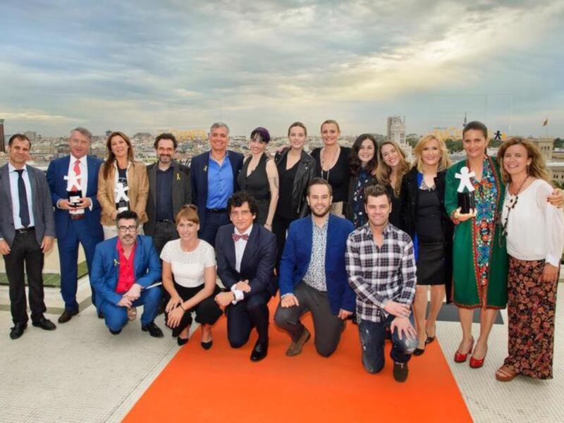 Equipo de artistas y profesionales posando en una terraza con vistas panorámicas de la ciudad.