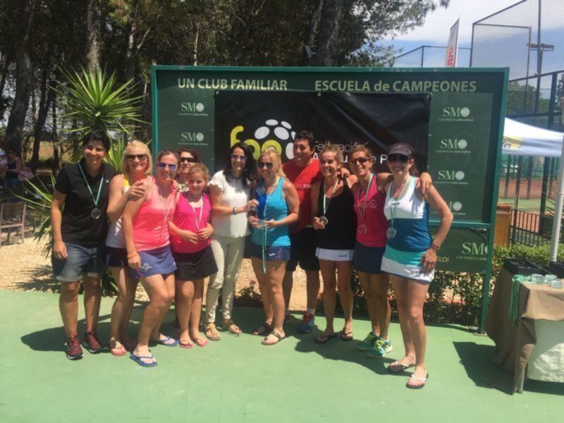 Equipo de tenis celebrando una victoria con medallas en un torneo familiar.