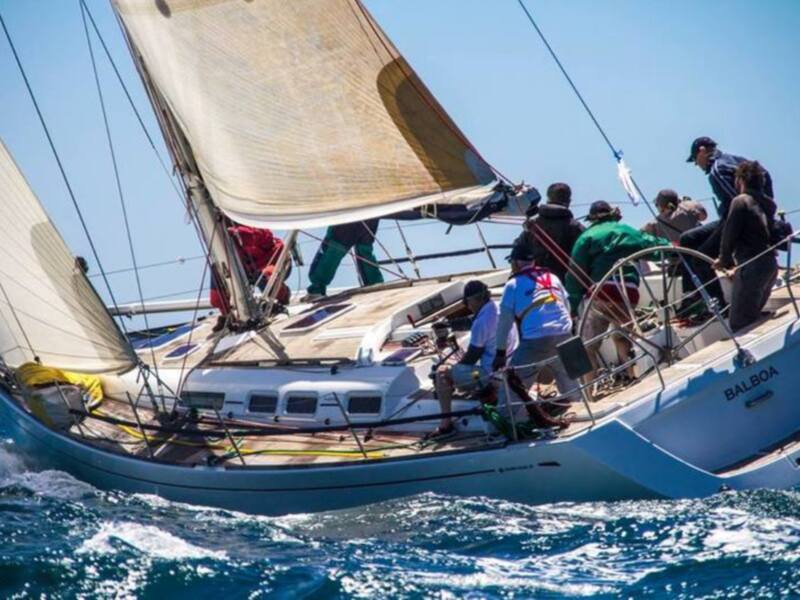 Barco de vela navegando en el mar con el equipo de tripulación en la cubierta.
