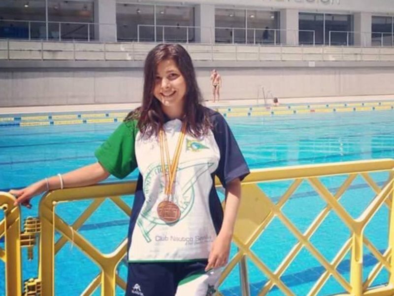 Campeona de natación posa orgullosa en la piscina municipal con su medalla de oro.