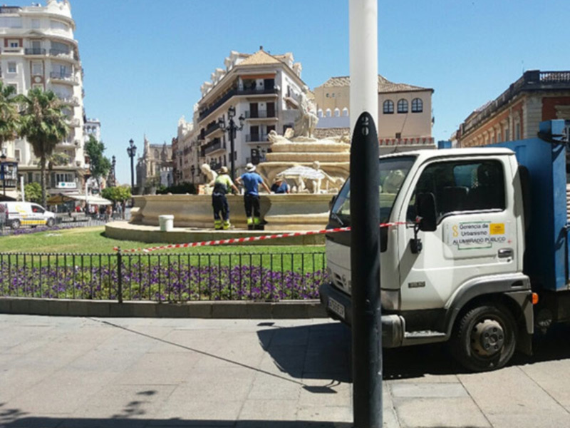 Plaza con fuente y edificios históricos, con un camión de limpieza en primer plano.