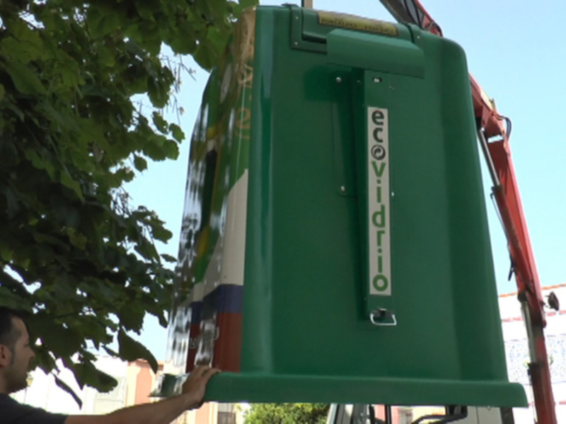Recogida de contenedores verdes para reciclaje en una calle urbana.