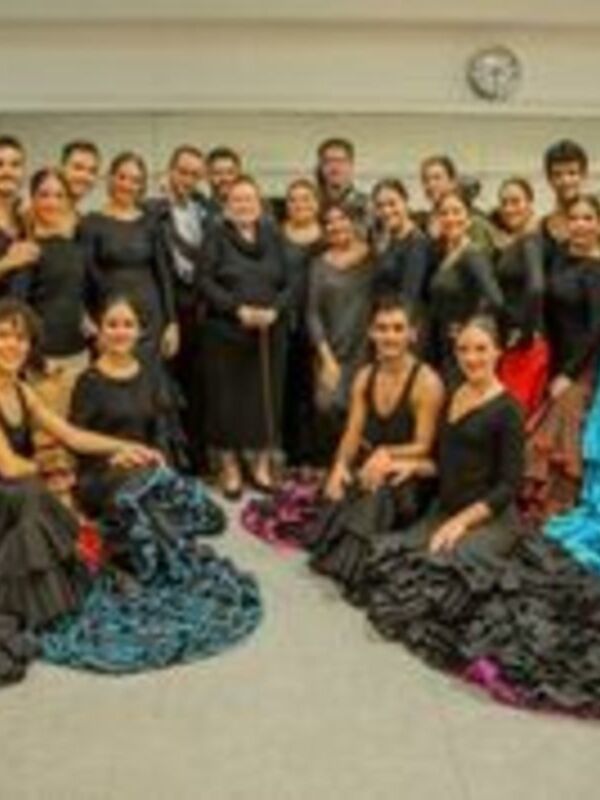 Una agrupación de bailarines en trajes tradicionales posando juntos, destacándose la variedad de colores y estilos en sus vestidos.
