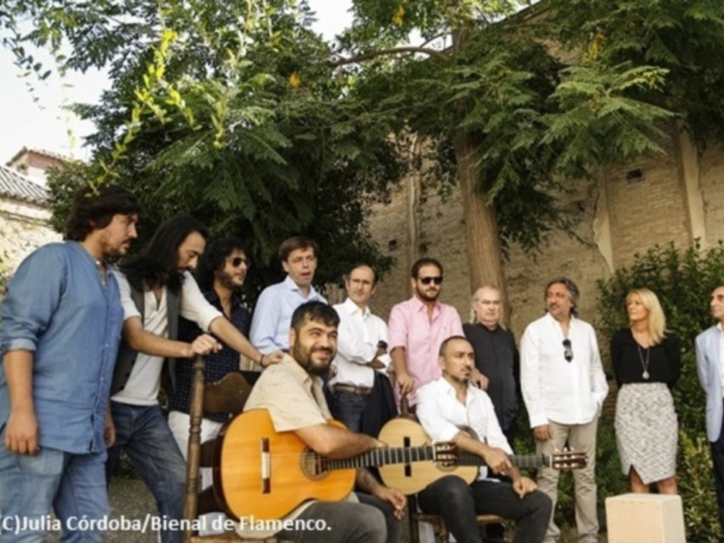 Grupo de músicos posando al aire libre con instrumentos, en el marco de la Bienal de Flamenco.
