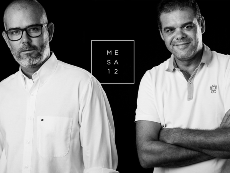 Dos hombres en blanco y negro con el texto "MESA 12" en el centro.