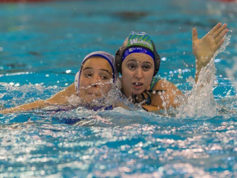 Jugadoras de waterpolo en acción durante un partido en piscina.