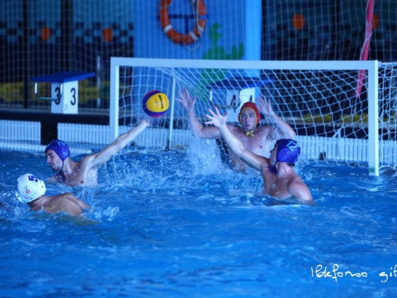 Jugadores de waterpolo en acción durante un partido, intentando controlar el balón en el agua.