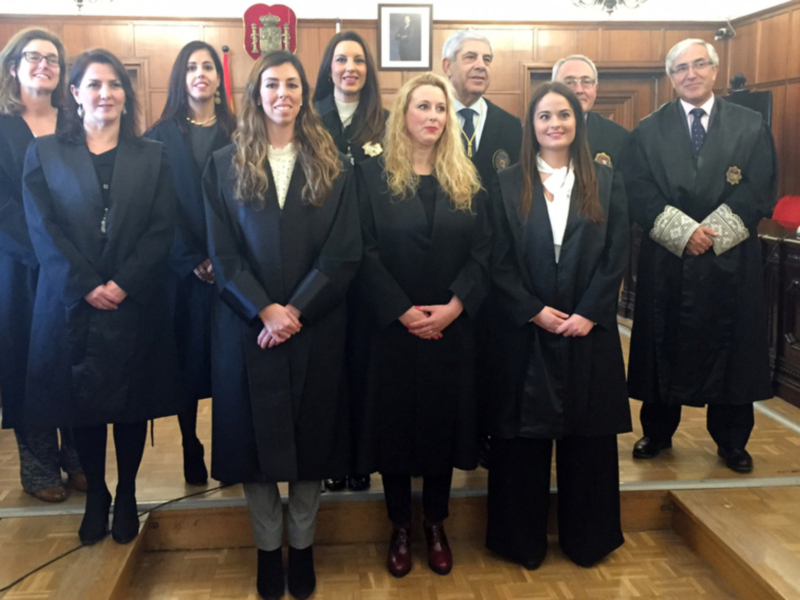 Grupo de profesionales en trajes de abogados y jueces posando en un tribunal.