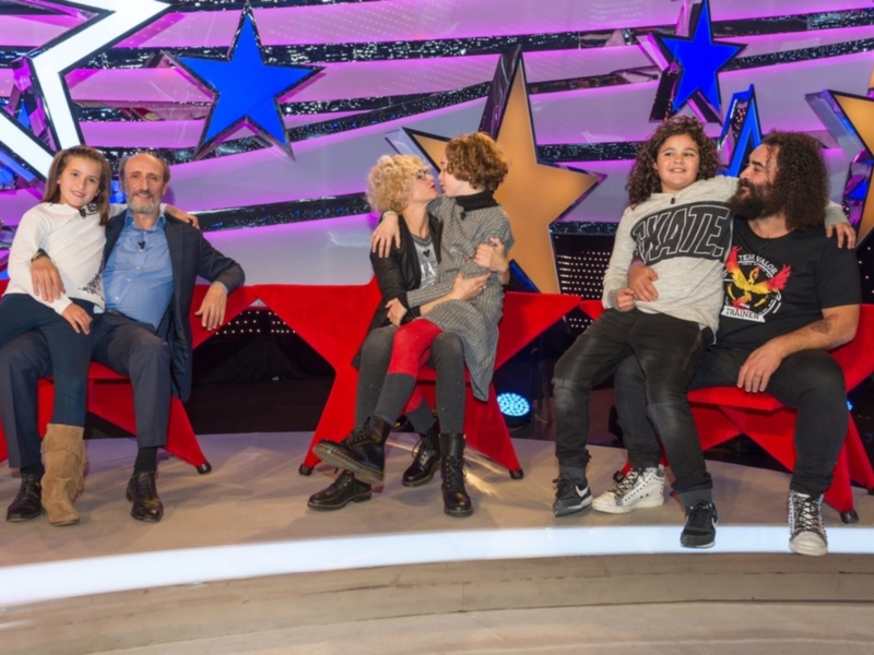 Personajes en un escenario con estrellas y luces, posando para una foto en un evento televisivo.