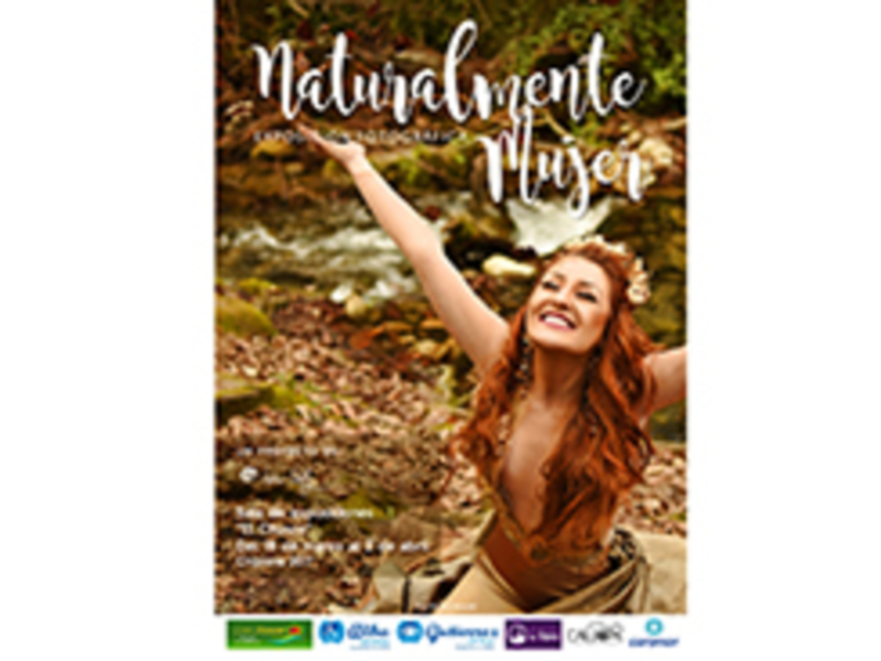 Una mujer con cabello rojo y una corona de hojas en la cabeza, extendiendo su brazo hacia el cielo. La imagen está ambientada en un bosque con árboles y hojas caídas, junto a un río. La frase "Naturalmente" está escrita en la parte superior de la imagen.