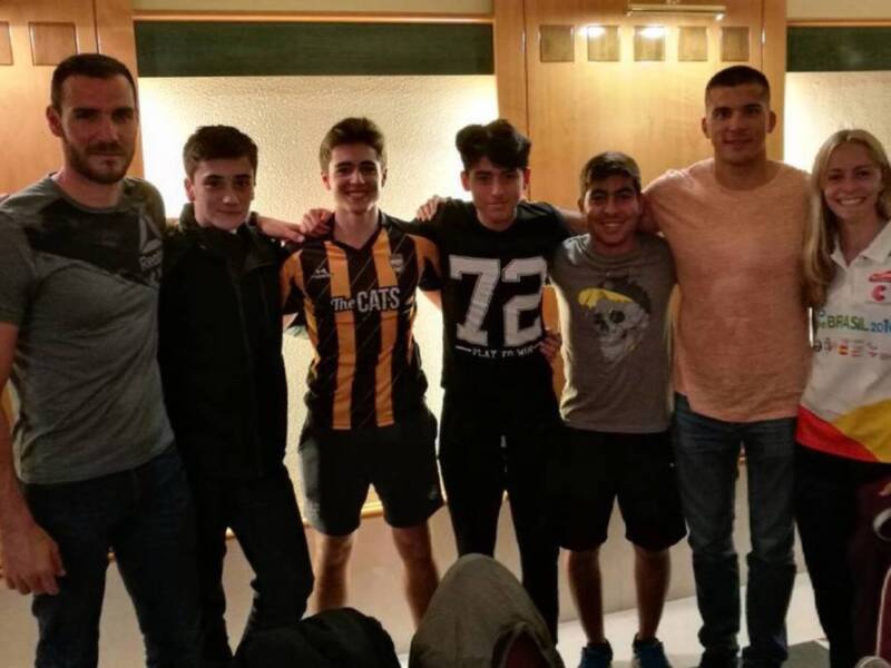 Equipo de atletas posando juntos en una reunión o evento deportivo, con camisetas que indican su afiliación a 'The CATS' y 'Brasil 2016'.
