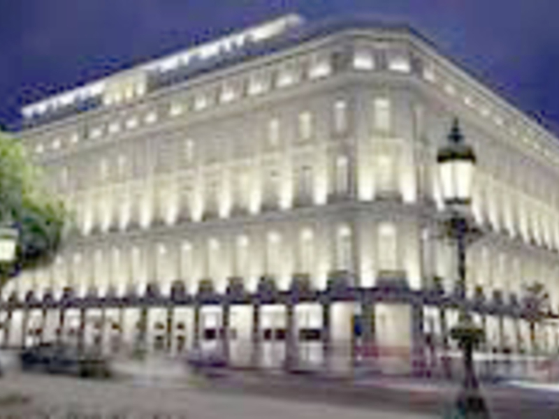 Edificio iluminado por la noche, con arquitectura clásica y luces brillantes en las ventanas.