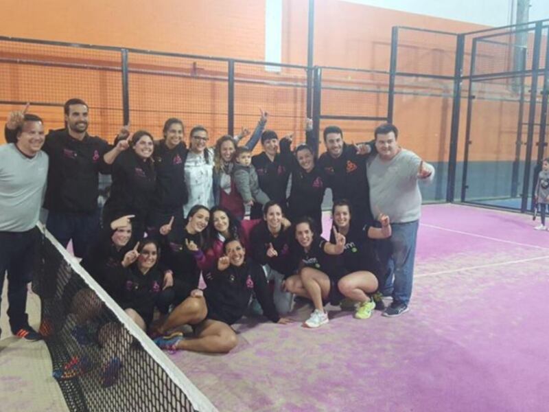Equipo de padel celebrando juntos en una cancha de padel.