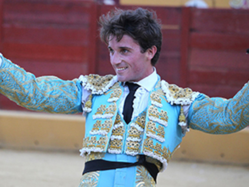 Joven torero celebrando con un pañuelo en la plaza de toros.