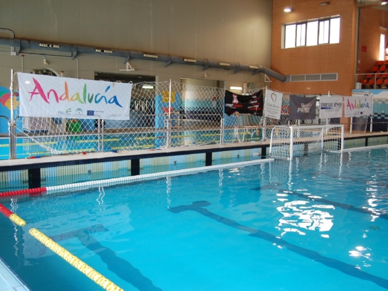 Piscina interior con bandera de Andalucía y anillos de natación.