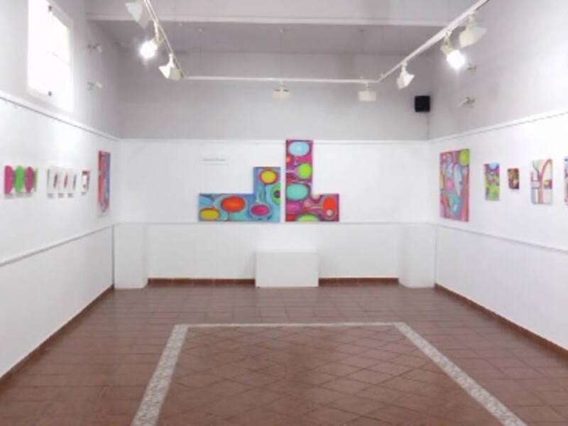 Exposición de arte moderno en una galería con obras de colores vibrantes y formas geométricas.
