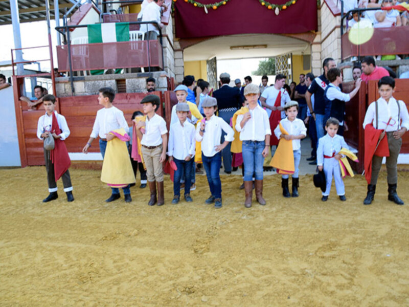 Jóvenes participantes en una feria o celebración tradicional, vestidos con trajes típicos y sombreros.